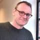 Sean Lock sports his glasses while posing for a picture.